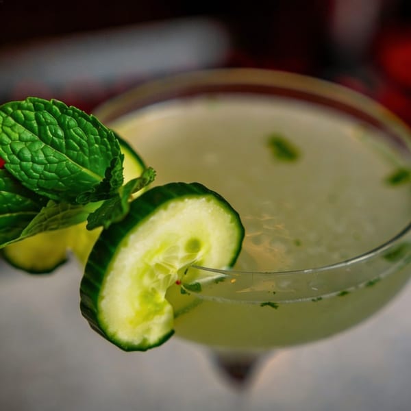 A refreshing cucumber and mint cocktail in a martini glass, garnished with cucumber slices.