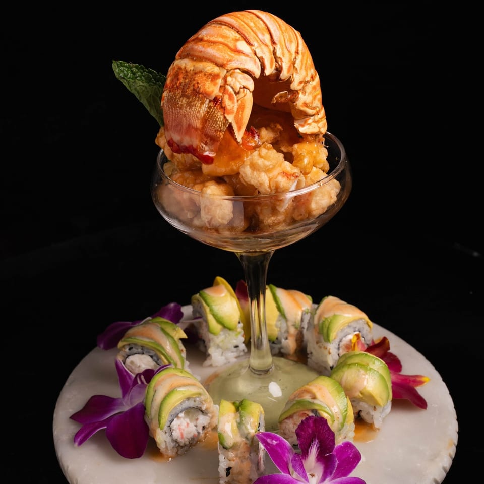 Neveyah Sushi and Thai's lobster tail and fried shrimp cocktail with avocado sushi rolls on a marble plate.